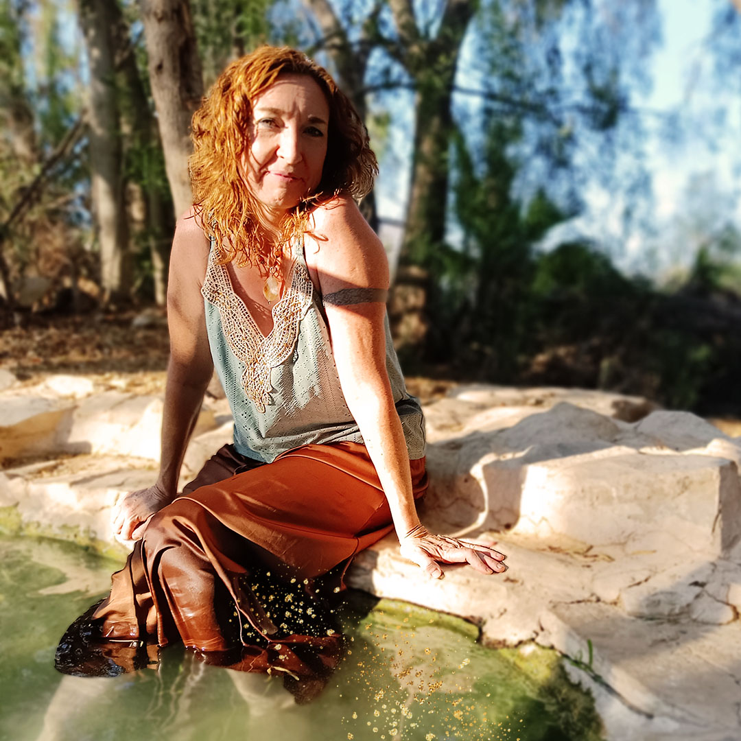 Sinéad Fine sitting by the edge of a pool with her legs in the water.